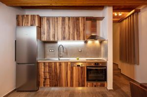 a kitchen with a stainless steel refrigerator and wooden cabinets at Redstone Luxury Villas in Theológos