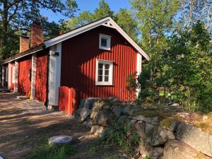 uma casa vermelha com uma parede de pedra em frente em Nedanby | Cottage | Idyllic location | Porch | Grill em Edsbro