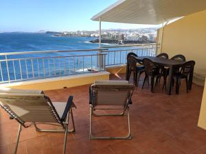 a balcony with a table and chairs and the ocean at Primera linea con amplia terraza in Melenara
