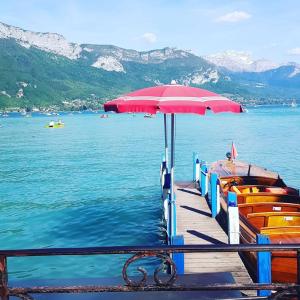 a dock with a red umbrella on the water at Studio dans résidence de tourisme*** in Giez