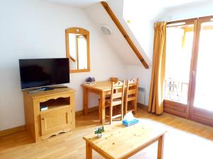 a living room with a tv and a wooden table at Studio dans résidence de tourisme*** in Giez