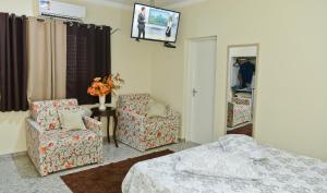 a bedroom with a bed and two chairs and a tv at Dmarco Hotel in Paraguaçu Paulista