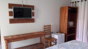a room with a desk and a tv on a wall at HOTEL ABAPORU in Adamantina