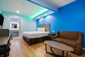 ハンブルにあるAmericas Best Value Inn- Aldine Westfieldのベッド、ソファ、テーブルが備わるホテルルームです。