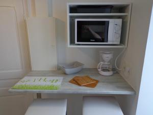 a kitchen with a counter with a microwave and a cake at Appartement d'Hôtes in Guéret