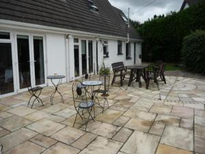 un patio de piedra con mesas y sillas en Carrigshane House, en Midleton