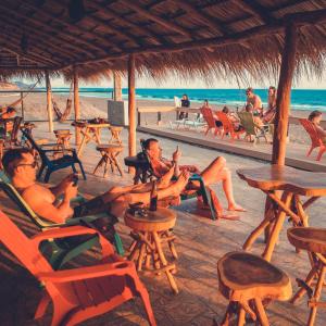 um grupo de pessoas sentadas em cadeiras na praia em The Barrel Hostel em Popoyo