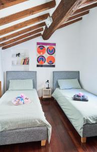 2 łóżka w pokoju z białymi ścianami i drewnianą podłogą w obiekcie La Casa di Giulia-Family Apartment w mieście Parma