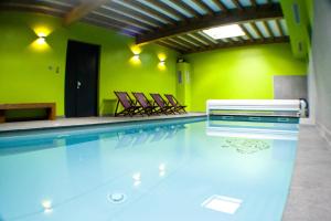 uma piscina com cadeiras num quarto com paredes verdes em Gite Roche Des Ducs avec Piscine toute l'année, Spa, Sauna, Hammam em Rochesson