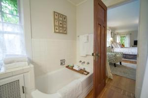 a white bathroom with a tub and a bedroom at Warm Springs Inn & Winery in Wenatchee