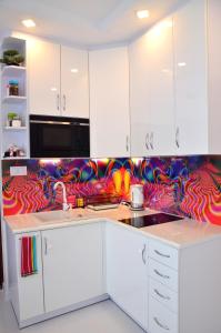 una cocina con armarios blancos y una pared colorida en Apartament Pegaz, en Gniezno