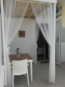 プレシッチェにあるB&B Suites Via del Mareのダイニングルーム(テーブル、白いカーテン付)