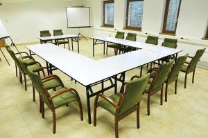 a conference room with tables and chairs and a screen at Völgyikút Ház in Veszprém