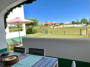 a table with an umbrella and a view of a field at Charming Apartment with Private Garden & Pool in Vilamoura