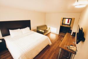 a bedroom with a bed and a chair and a television at Hotel Moncton in Moncton