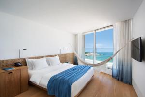 um quarto de hotel com uma cama e uma grande janela em Hotel Arpoador no Rio de Janeiro