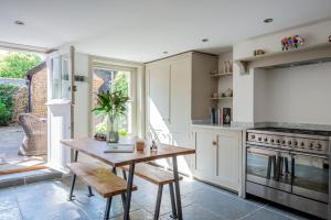 a kitchen with white cabinets and a wooden table at A Luxury Retreat in the Heart of Arundel in Arundel