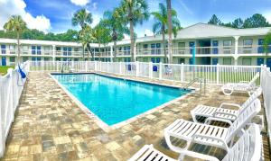 una piscina con sillas blancas y un complejo en Motel 6-Starke, FL, en Starke