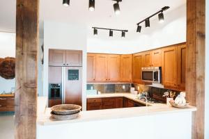 a kitchen with wooden cabinets and stainless steel appliances at Pacific Soul Eco-Luxe Vacation Home in Ucluelet