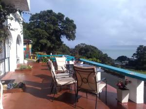 a row of chairs on a balcony with a swimming pool at La Casa Te Puru Lodge in Te Puru