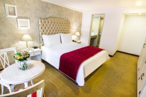 波哥大汉密尔顿GHL酒店的酒店客房配有一张带红色毯子和桌子的床。