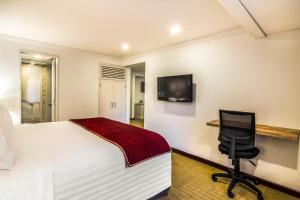 Schlafzimmer mit einem Bett, einem Schreibtisch und einem TV in der Unterkunft GHL Hotel Hamilton in Bogotá