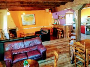 a living room with a leather couch and a fireplace at Albergue Olasenea Aterpea in Zubieta