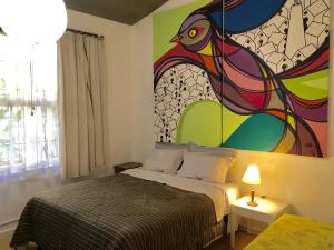 a bedroom with a bed with a painting on the wall at Residência Acolhedora in Porto Alegre
