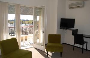 a room with two chairs and a table and a television at Mercedes Rambla Hotel in Mercedes