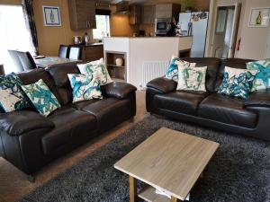 a living room with two leather couches and a coffee table at Trevellian - Boutique Secluded Scenic Lodge in Dawlish