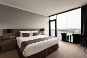 
a hotel room with a large bed and a large window at Lakes Hotel in Adelaide
