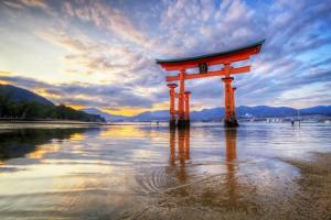 una puerta torii naranja en el agua en una playa en Hirose inn F+ en Hiroshima