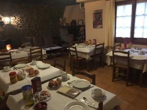 un restaurante con mesas blancas y sillas con comida. en Cal Mateu, en Urtx
