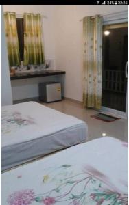 sypialnia z 2 łóżkami i oknem z zasłonami w obiekcie Benjamat Resort w mieście Sakon Nakhon