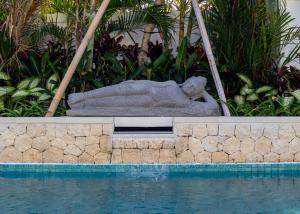 
a statue of a bear sitting on a bench in front of a pool at Aloha Beach House Bingin in Uluwatu
