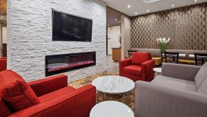 a living room with red chairs and a fireplace at Best Western Plus Hinton Inn & Suites in Hinton