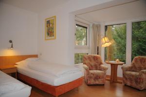 a bedroom with a bed and two chairs and a window at Hotel Hubertus in Hannover +16 photos