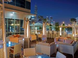 a restaurant with chairs and tables and a city skyline at Pullman Dubai Jumeirah Lakes Towers in Dubai