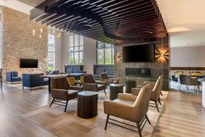 a lobby with chairs and tables and a flat screen tv at Cambria Hotel Ft Collins in Fort Collins