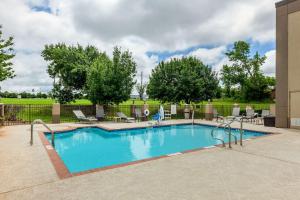 a swimming pool in a courtyard with chairs and trees at Quality Suites Sherman in Sherman