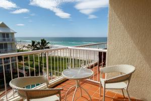 
a patio area with chairs, a table, and a balcony at Crystal Beachfront Apartments in Gold Coast
