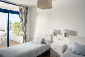 a white bedroom with two beds and a balcony at Villas de la Marina in Playa Blanca
