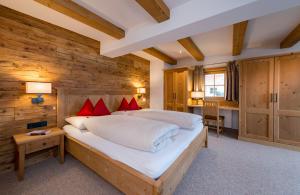 1 dormitorio con 1 cama grande y pared de madera en Alpengasthof Rossmoos, en Alpbach