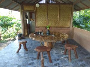 a wooden table and stools on a patio at Bali mountain forest cabin in Penebel