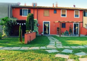 een rood huis met een tuin en een patio bij Il Cantuccio in Cascina