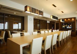 a dining room with a large wooden table and white chairs at Hotel Sorriso Hamamatsu in Hamamatsu