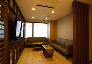 a living room with a couch and a tv at Hotel Sorriso Hamamatsu in Hamamatsu