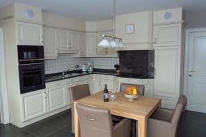 a kitchen with white cabinets and a table with a bowl of fruit at Vakantiewoning Pelterheggen in Grote Heide