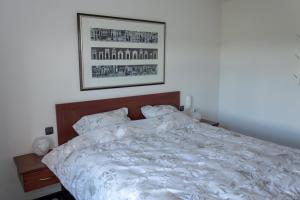 a bedroom with a white bed with a picture on the wall at Vakantiewoning Pelterheggen in Grote Heide