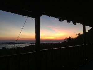 a view of a sunset from a house window at Cocohuts Hotel in Karimunjawa